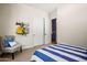 Bright bedroom with a blue striped bedspread, coat rack, and a chair next to the closet at 11878 N Hershey St, Surprise, AZ 85388