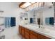 Bathroom with double sinks, wood cabinetry, marble counters, and large mirrors at 12001 N 53Rd Ave, Glendale, AZ 85304