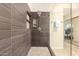 Modern shower with gray tiling and a glass door, adjacent to a room with a desk, offering a contemporary bathroom design at 1401 E Brentrup Dr, Tempe, AZ 85283