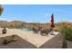 View of pool area featuring a dining set with red umbrella, desert landscaping, and mountain views at 14939 S 185Th Ave, Goodyear, AZ 85338