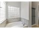 Bright bathroom featuring a soaking tub with tile surround and a decorative glass block window at 16155 E Glenview Pl, Fountain Hills, AZ 85268