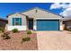 Charming single-story home featuring a blue garage door and decorative stone landscaping at 17454 W Red Fox Rd, Surprise, AZ 85387