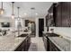Modern kitchen with dark cabinetry, stainless steel appliances, and an island overlooking the living area at 17454 W Red Fox Rd, Surprise, AZ 85387