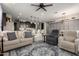 Open-concept living room showcasing stylish furniture, a ceiling fan, and seamless flow to the kitchen and dining areas at 17454 W Red Fox Rd, Surprise, AZ 85387