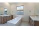 This bathroom includes double sinks with wooden cabinets, a modern soaking tub, and hexagon tile floors at 21430 W Meadowbrook Ave, Buckeye, AZ 85396