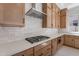 This kitchen features wooden cabinets, white subway tile backsplash, and a stainless steel cooktop at 21430 W Meadowbrook Ave, Buckeye, AZ 85396