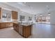 Open-concept kitchen featuring an island with stainless steel appliances, wood cabinetry, and bright tile flooring at 21430 W Meadowbrook Ave, Buckeye, AZ 85396