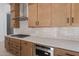 This kitchen showcases wooden cabinets, a modern range hood, white countertops, and a sleek gas cooktop at 21430 W Meadowbrook Ave, Buckeye, AZ 85396