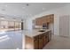 Open-concept kitchen with an island, stainless steel appliances, wood cabinetry, and bright tile flooring at 21430 W Meadowbrook Ave, Buckeye, AZ 85396