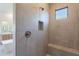 A large walk-in shower features neutral tile, a built-in bench and window for natural light at 21430 W Meadowbrook Ave, Buckeye, AZ 85396