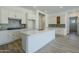 Modern white kitchen with island, stainless appliances, gray backsplash, and ample cabinet space at 21450 W Meadowbrook Ave, Buckeye, AZ 85396