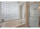Bright bathroom featuring a soaking tub with glass block window and glass enclosed shower at 3120 E Squaw Peak Cir, Phoenix, AZ 85016