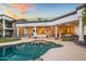 A luxurious pool with a stone outdoor bar, surrounded by windows and a patio at 3630 E Coconino Ct, Phoenix, AZ 85044