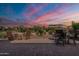 Charming back patio with brick pavers, seating, and desert landscaping under a beautiful sunset sky at 37036 N Stoneware Dr, Queen Creek, AZ 85140