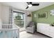 Bright Bedroom with a white crib, a gray glider chair, and green accent wall at 4036 E Captain Dreyfus Ave, Phoenix, AZ 85032
