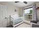 Bright Bedroom with a white crib, a gray glider chair, and view to the neighborhood at 4036 E Captain Dreyfus Ave, Phoenix, AZ 85032