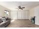 Well-lit bedroom with wood-look flooring, a ceiling fan, a couch, and three closets for storage at 4036 E Captain Dreyfus Ave, Phoenix, AZ 85032