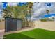 Backyard featuring a storage shed, green artificial turf and desert landscaping at 4036 E Captain Dreyfus Ave, Phoenix, AZ 85032