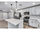 Modern kitchen featuring stainless steel appliances, white cabinets, and a stylish island with pendant lighting at 4207 W Poinsettia Dr, Phoenix, AZ 85029