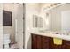 Bathroom with wood cabinets, dual sinks, a mirror, and a separate toilet area at 4419 W Lodge Dr, Laveen, AZ 85339