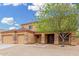 Tan two-story home with a three-car garage and low maintenance rock landscaping at 4419 W Lodge Dr, Laveen, AZ 85339