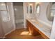 Bathroom featuring a wood floor and vanity with double sinks, mirrors, and a window for natural light at 4773 E Hopi St, Phoenix, AZ 85044
