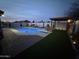 Backyard at night with a lighted pool, a pergola, and lush landscaping, creating a relaxing outdoor ambiance at 5361 N 77Th Ln, Glendale, AZ 85303