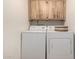 Bright laundry room with stacked washer and dryer and upper cabinets for storage at 5741 N 44Th Ln, Glendale, AZ 85301