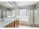 Bright bathroom featuring a double sink vanity, soaking tub, and glass-enclosed shower at 6615 S 25Th Dr, Phoenix, AZ 85041