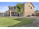 Backyard featuring a lush lawn, mature landscaping, and a cozy covered patio at 7628 W Donald Dr, Peoria, AZ 85383