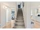 Bright stairway leading to an exercise room and the kitchen featuring gray carpet and white walls at 7732 E Coolidge St, Scottsdale, AZ 85251