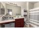 Bathroom with cherry vanity, white sink, three-pane mirror, and shower with a grey curtain at 8105 W Groom Creek Rd, Phoenix, AZ 85043