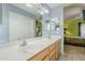 Bathroom featuring a double sink vanity, a large mirror, blue walls and view into the main bedroom at 10318 W Luke Ave, Glendale, AZ 85307