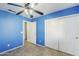 Bright blue bedroom with sliding door closet, ceiling fan and tile floors at 10318 W Luke Ave, Glendale, AZ 85307