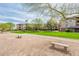 Exterior view of a condominium complex with green grass, covered parking, mature trees and desert landscaping at 14950 W Mountain View Blvd # 5312, Surprise, AZ 85374