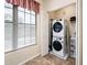 Laundry area with a modern stackable washer and dryer set and storage shelf, all illuminated by natural light at 14950 W Mountain View Blvd # 5312, Surprise, AZ 85374