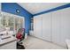 Bright office featuring a blue accent wall, white built-in desk and shelving, and shutters at 15546 W Whitton Ave, Goodyear, AZ 85395