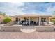 This backyard is landscaped with desert plants, a covered patio, and a stucco wall at 16406 W Peppertree Ct, Surprise, AZ 85387