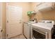 This laundry room is equipped with a washer, dryer, shelving, and a door at 16406 W Peppertree Ct, Surprise, AZ 85387