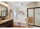 Bright bathroom features a soaking tub, elegant chandelier, and a separate glass-enclosed shower at 2328 N 123Rd Ln, Avondale, AZ 85392