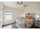 Bright bedroom featuring wood floors, a ceiling fan, and a large window with natural light at 2328 N 123Rd Ln, Avondale, AZ 85392