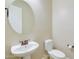 Half bath with a pedestal sink, a round mirror, and a toilet at 2830 E Fruitvale Ave, Gilbert, AZ 85297