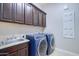 Modern laundry room with dark wood cabinets, washer and dryer, and a utility sink at 2830 E Fruitvale Ave, Gilbert, AZ 85297