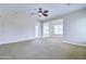 Spacious living room with neutral walls and carpet, ceiling fan, and a glass door at 2830 E Fruitvale Ave, Gilbert, AZ 85297