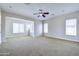 Bright, spacious living room featuring a ceiling fan, neutral carpeting and many large windows at 2830 E Fruitvale Ave, Gilbert, AZ 85297