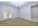 Bright living room with carpeted floors, a modern chandelier, and access to the outside through French doors at 2830 E Fruitvale Ave, Gilbert, AZ 85297