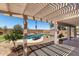 Inviting backyard with a refreshing pool, covered patio, and lush landscaping, ideal for relaxation and entertaining at 34990 N Spur Cir, San Tan Valley, AZ 85144