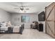 Cozy bedroom featuring a ceiling fan, a comfortable bed, wall decor, and a sliding barn door at 34990 N Spur Cir, San Tan Valley, AZ 85144