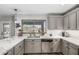 Bright kitchen features gray cabinets, stainless appliances, quartz countertops, a window and stylish backsplash at 34990 N Spur Cir, San Tan Valley, AZ 85144