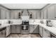 A modern kitchen with gray cabinets, stainless steel appliances, quartz countertops, and a stylish backsplash at 34990 N Spur Cir, San Tan Valley, AZ 85144